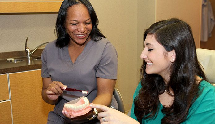 hygienist showing patient proper tooth care.